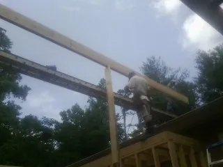 Carpenter setting a ridge beam over a new addition frame — Ice Dam Removal by Roofing Brothers in Postville