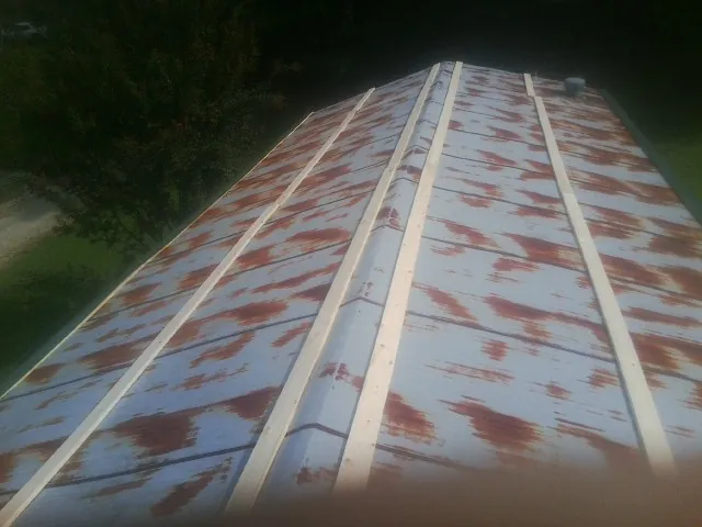 Rusted metal roof panels with new wood purlins before replacement — Storm Damage Roof Repair in Postville by Roofing Brothers