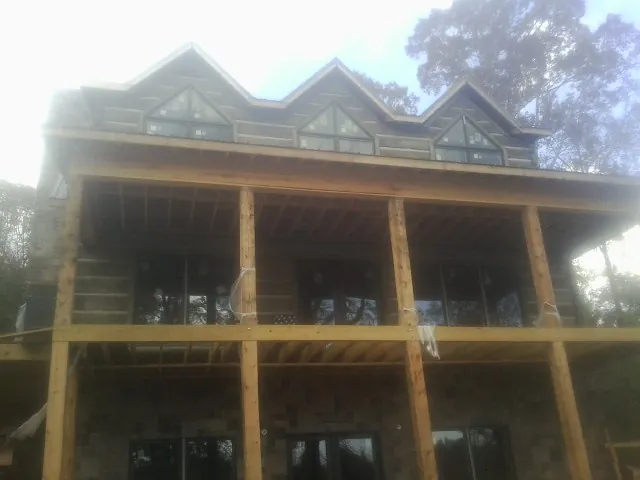 Dormers and porch framing on a large log home under construction — Roof Coating work by our crew in Postville