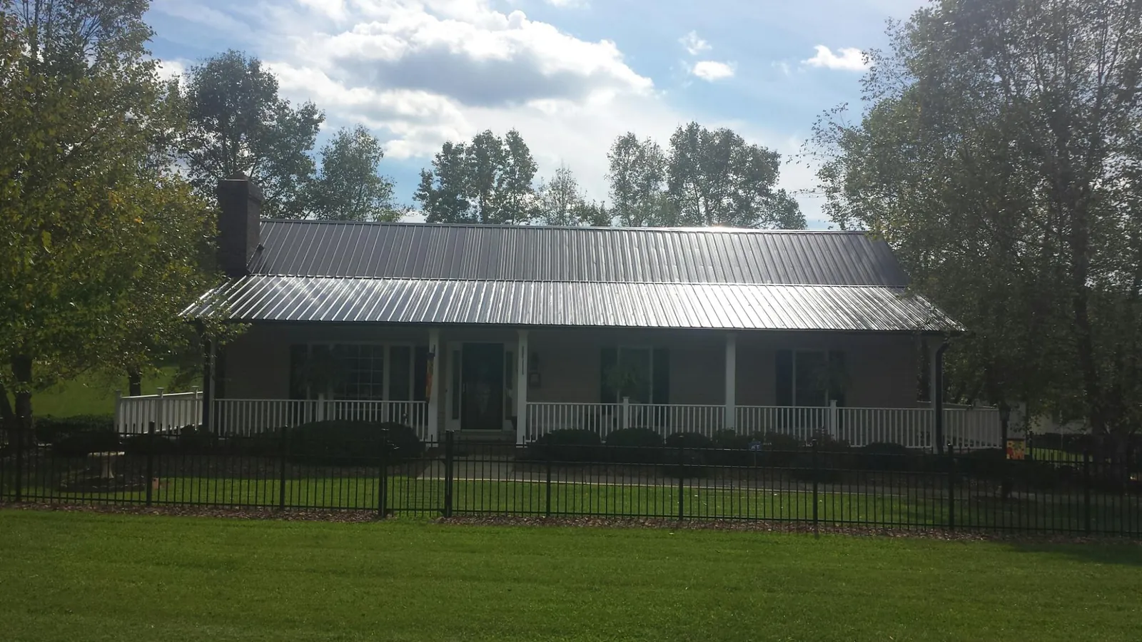 Gray metal roof on a brick ranch with a full width front porch — Gutter Guard Installation work by our crew in Postville