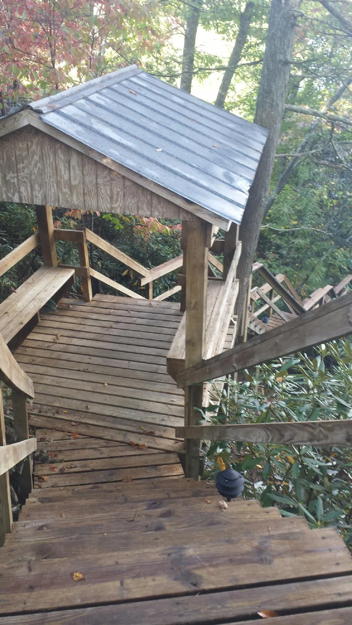 Metal roofed shelter over wooden steps on a wooded walkway — Skylight Repair & Installation work by our crew in Postville