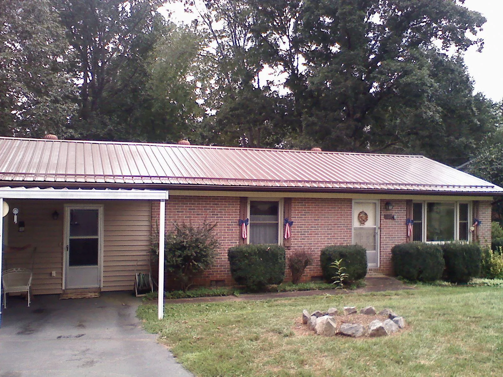 Bronze metal roof and carport on a brick ranch home — Roof Repair work by our crew in Postville