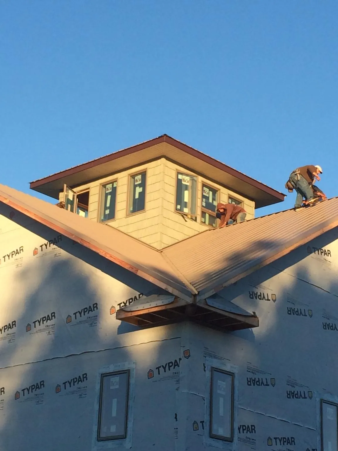 Roofers working around a rooftop cupola on a new metal roof at sunset — Roof Waterproofing in Postville by Roofing Brothers